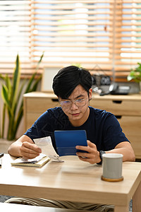 严肃的亚洲人在客厅使用计算货币银行贷款和管理费用财务图片