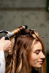 女美发师在美容院里 为一位棕色头发的年轻caucasian女子卷发卷发器发型师沙龙滚筒梳妆台理发顾客造型理发师女孩图片