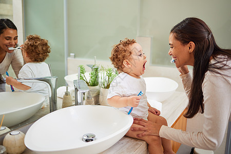 妈妈教宝宝刷牙 在家里的浴室柜台上 脸上挂着干净的笑容 儿童健康的口腔卫生意味着使用适合儿童的牙膏 牙刷和牙科常规图片
