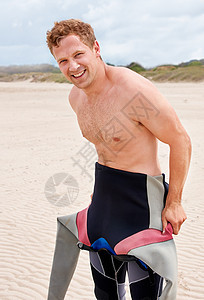 我觉得这是第二层皮肤 一个年轻冲浪者在海滩上穿上湿衣服的身子冒险海洋旅行活动冲浪青年运动闲暇沙滩假期图片