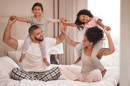 早上 家人在床上放松 兴奋和亲密 穿着他们在家里的睡衣 年轻的黑人父母和女儿在卧室里无忧无虑 表达爱意 一起休息图片