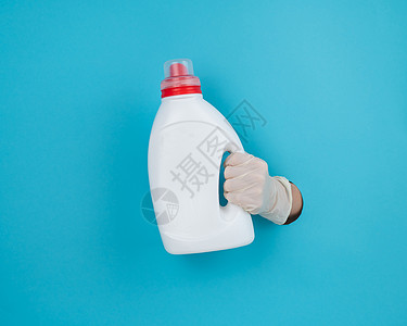 一个女人拿着一瓶白色的洗涤剂 女人的手从蓝纸背景中伸出来蓝色房子家庭女性卫生工具瓶子产品家政家务图片