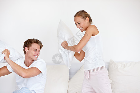 一对穿着睡衣的年轻夫妇 和枕头打架了 你觉得呢? - 对啊!背景图片