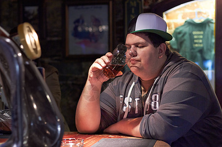 在一杯啤酒中沉溺他的痛苦 一个在酒吧独自饮酒的年轻人图片