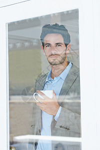 早上喝咖啡很愉快 一个英俊的年轻男人在看窗外时喝咖啡的肖像 (笑声)图片