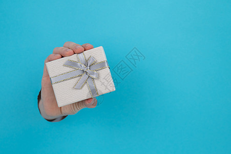 女人的手棍从蓝纸背景和礼物盒里拿出来展示女孩眼泪蓝色女士纸板盒子惊喜手臂丝带图片