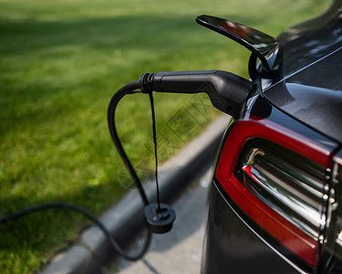 黑色电动汽车在夏季向户外充电杂交种机动性引擎力量电池车站控制环境排放车辆图片