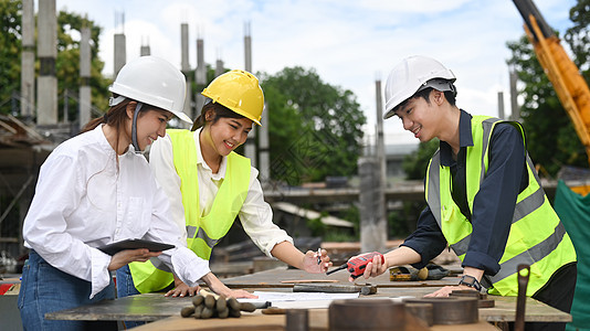 建筑师小组和工程师监督员身着安全头盔 在施工工地一起检查工程计划的工作情况图片