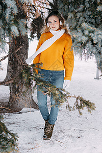 冬天外面穿黄色毛衣的金发女青年 在雪林里穿着冬装散步的十几岁少女自由围巾雀斑暴风雪肖像耳机喜悦衣服女性靴子图片