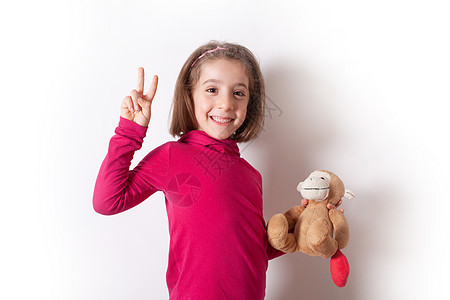 一个快乐的小女孩 拿着猴子果酱 展示了胜利的征兆图片