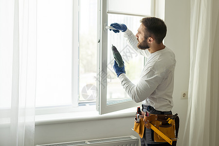 英俊的年轻人在新的房屋建筑工地安装海湾窗户塑料男性维修建设者工人服务男人企业住宅办公室图片