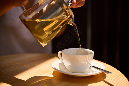 从茶壶到茶杯的绿色异国茶叶 更贴近地倒上健康的抗氧化剂图片