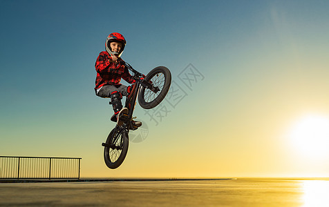 一个十几岁的BMX赛马骑士 在滑冰公园的泵轨上表演把戏街道公园乐趣行动特技自行车兔子竞赛天空太阳图片