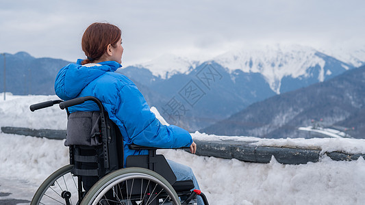 看着一位坐在轮椅上的女人 在冬天在山里旅行保健四肢山脉车轮登山者事故享受假期女性椅子图片