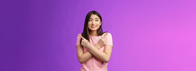 开朗胆小可爱的亚洲女孩 看起来很温柔 微笑着凝视着双手交叉的胸膛 向侧面指着 向左向右展示 做出决定 收集信心选择 紫色背景护理图片