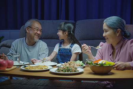 家庭外祖父母和孙女在餐桌上吃饭 在家里玩得开心图片