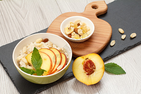 石板上有坚果和新鲜桃子的高梁沙拉早餐谷物植物营养高粱饮食腰果收据木板麸质图片