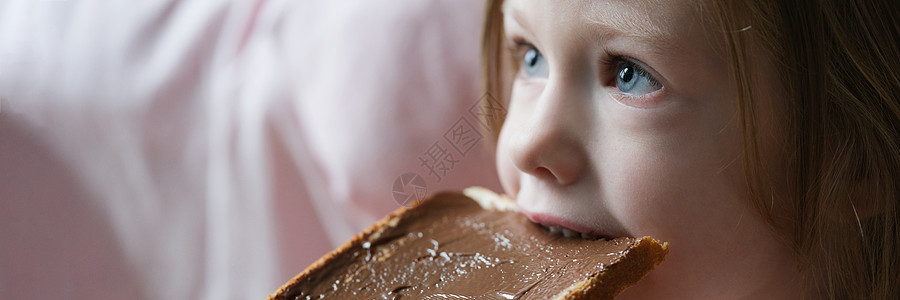可爱的小女孩 吃面包和巧克力意面 在顶上 美味甜点图片
