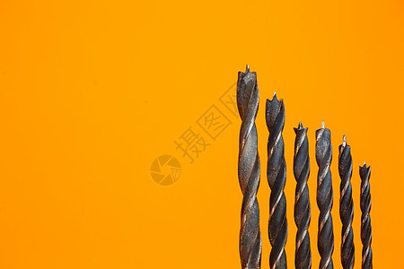 橙色背景钻探不同大小木柴的钻孔 建筑工具建造工具工作工程乐器收藏钻头木工宏观尺寸螺旋机器图片