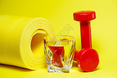 红色哑铃 一杯水 黄色地毯 彩色背景 体育 能源饮料 健身房设备桌子橙子瓶子茶点重量玻璃杯子薄荷浆果小地毯图片