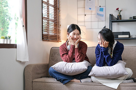 快乐的亚洲女性朋友在家坐在沙发上 两个年轻女人在沙发上闲聊 分享秘密 讨论生活和关系 友谊信任理念女孩闲暇八卦女朋友家庭房间长椅图片