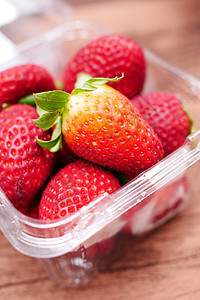 将红草莓放在桌上的塑料袋中图片