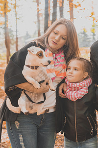 秋天公园的母亲和女儿 女孩拥抱着她的杰克·鲁塞尔泰瑞狗 世代 宠物和家庭概念图片