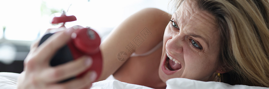 女人躺在床上 手拿着闹钟尖叫着叫喊图片