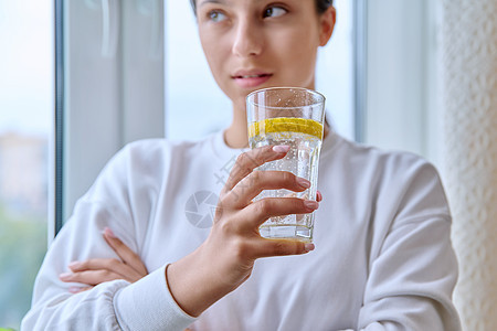 在年轻女性手中用柠檬杯水紧闭的杯子成人排毒饮食水果饮料果汁补品女孩液体皮肤图片