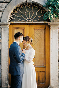 Groom亲吻新娘前额 靠近一扇拱门图片