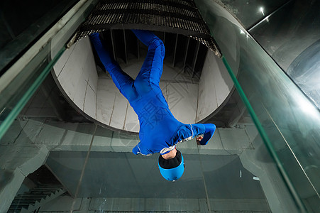 身穿制服和戴防护头盔的人喜欢在风道飞行 自由坠落模拟器培训师玻璃讲师跳伞溪流乐趣宇航员运动飞点套装图片