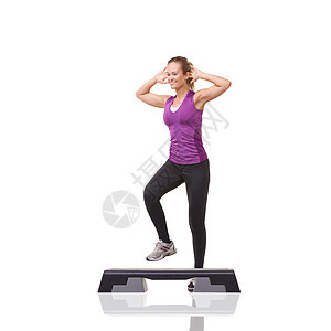 一位微笑的年轻女子 在白种背景下 在有氧运动步骤上做有氧健身术工作图片