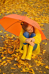 快乐的孩子坐在秋天公园女孩童年雨衣公园水坑花园乐趣下雨喜悦彩虹图片