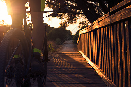 日落时 骑着山上自行车的骑手穿越桥图片