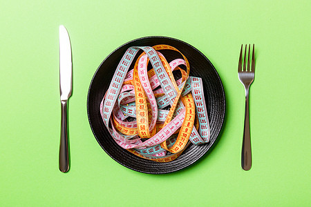 绿色背景板上彩色卷尺堆的顶部视图 具有复制空间的饮食概念图片