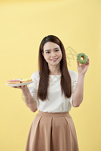 有魅力的女孩拿着新鲜甜甜圈 享受甜食的乐趣 心情好 饮食概念展示粉色手指手势情感微笑快乐图片