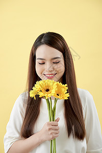 穿着白衬衫的漂亮女人 手里拿着黄色背景的鲜花 她微笑着大笑头发花朵女性雏菊黑色图片