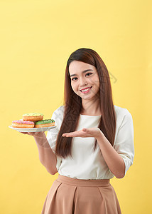 美丽的年轻女人微笑着拿着一盘装满美味彩色甜甜圈的盘子饮食甜点女性垃圾女孩小吃成人白色食物图片