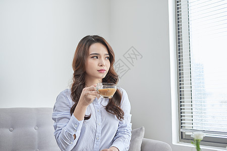 在沙发里放松 喝茶的开心女人咖啡女孩牛奶窗户女性杯子背景图片