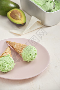 白色背景的圆锥形冰淇淋小松饼中绿色鳄梨冰淇淋勺 copy space冰淇淋奶油状茶点甜点食物桌子薄荷图片