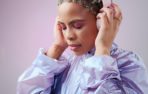 时尚 耳机和黑人女性在工作室粉红色背景下穿着复古蒸汽波衣服听音乐 用于青年样机广告的具有彩妆和音频技术的 Gen z 女孩模型图片