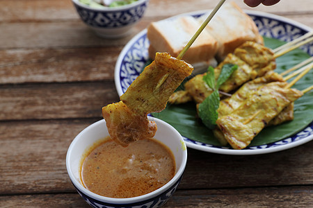 当地泰国食物猪肉沙戴 配有以木本为隔离的食人鱼酱炙烤餐厅烧烤街道花生沙爹沙拉美食午餐盘子图片