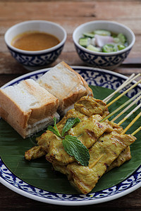 当地泰国食物猪肉沙戴 配有以木本为隔离的食人鱼酱盘子沙爹烧烤炙烤午餐辣椒餐厅沙拉美食街道图片