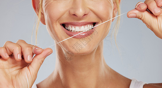 在灰色样机工作室背景下清洁口腔时使用牙线 牙齿健康和微笑的女人 带线模型的手用微笑照顾牙齿健康和口腔保健图片