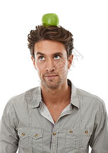 一个英俊的年轻人 平衡着头顶上的苹果 他却在脑海中吃东西图片
