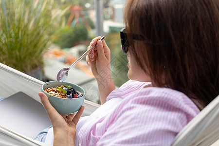 年轻女人吃辣椒布丁加果子和浆果排毒享受营养种子饮食坚果阳台喜悦酸奶女士图片