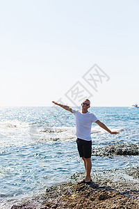 身穿白色T恤和短裤的太阳镜 有魅力的年轻男子 站在地中海海岸上男人衣服潮人打印运动海洋男性纺织品小样思维图片