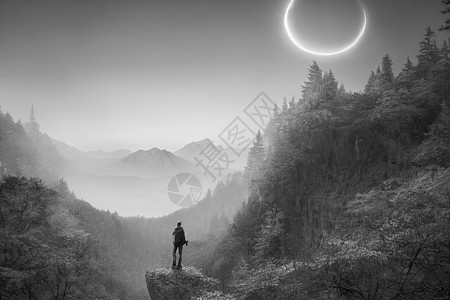 无畏的旅行者站在悬崖上 俯视秋天的森林和高雅的浅蓝山脉天空公园风景远足远足者男人游客岩石地标石头图片