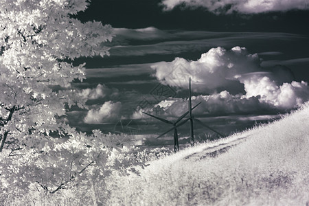 农村滚动山后面风力涡轮机的红外照片图片