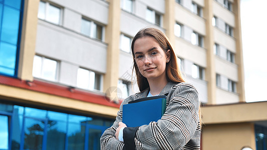 一名年轻女学生带着文件夹穿过城市 她手里拿着文件夹图片